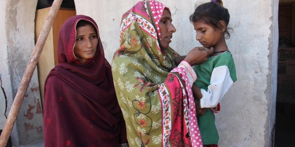 donne pakistane con veli colorati. a sinistra ragazza, al centro la madre con in braccio la figlia minore triste