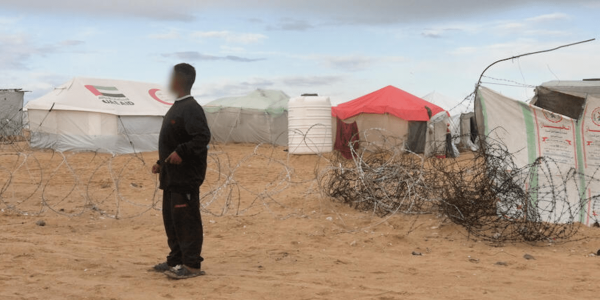 bambino a Gaza di fronte filo spinato e campo per sfollati