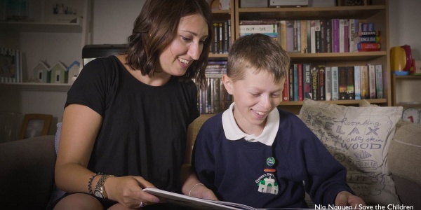 Una mamma e suo figlio leggono insieme un libro seduto sul divano di casa