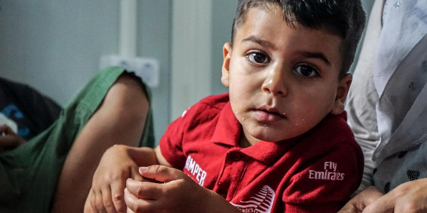 Bambino seduto, con indosso una t-shirt rossa