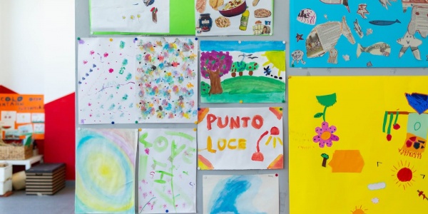 Disegni di bambini attaccati al muro in Punto Luce Save the Children