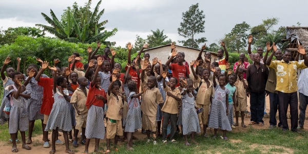 Comunita del cacao Ivoriana di bambini e adulti posa per una foto di gruppo davanti ad alcune case del villaggio