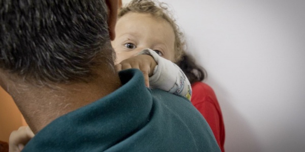 papà di spalle tiene in braccio bambino