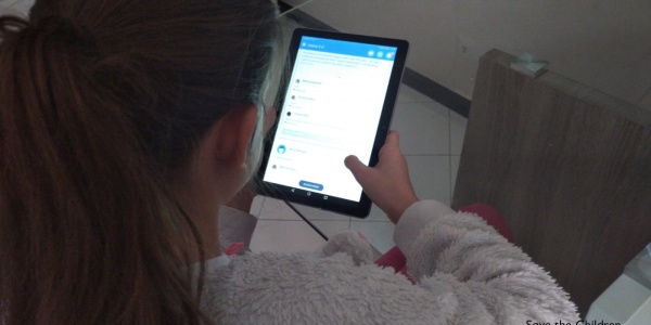 Bambina di spalle con pile bianco che guarda il tablet
