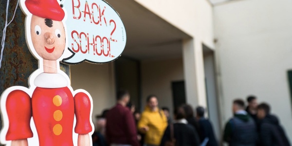 Cartello di pinocchio con fumetto della scritta "back to school" e persone in sfondo