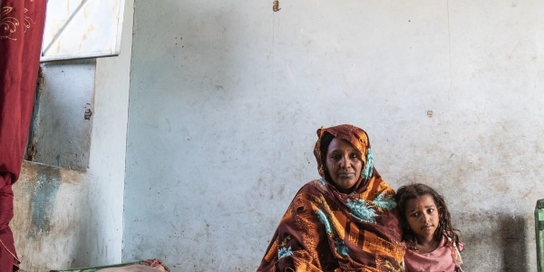 bambina seduta sul letto accanto alla madre in Sudan
