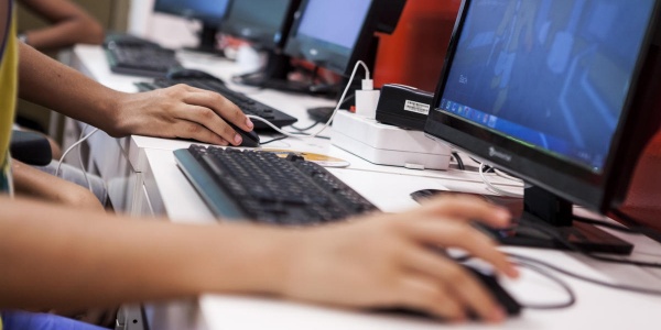 Mani di bambini sul mouse in una sala computer