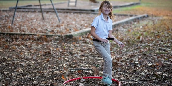 Bambina bionda gioca in un parco con cerchio