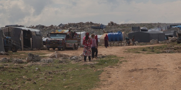 bambini di spalle in lontananza sullo sfondo di un accampamento di fortuna nel nord ovest della Siria