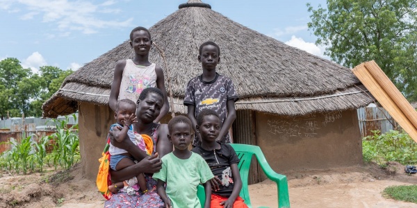 Famiglia sud sudanese in posa davanti alla propria capanna