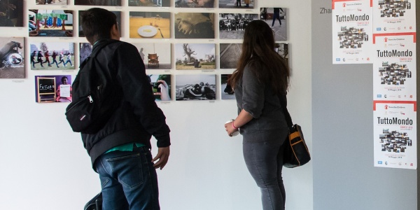 due ragazzi in un museo, in piedi, di spalle, guardano delle fotografie appese a un muro