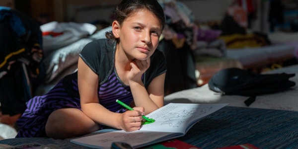 bambina accovacciata su un libro che cerca di studiare in un rifugio in Ucraina