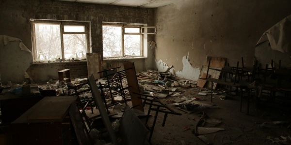scuola distrutta con banchi e sedie rotte 