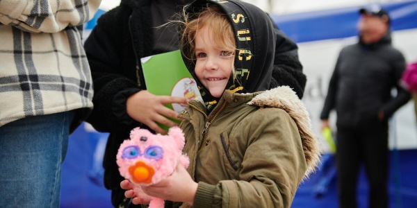 Bambina ucraina rifugiata sorride tenendo in mano un peluche
