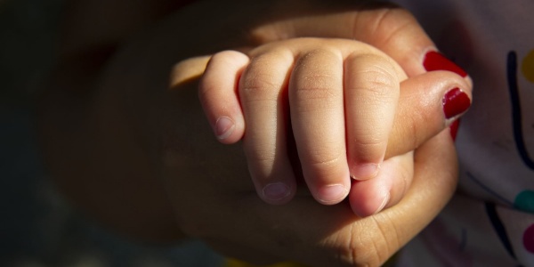 mano di donna con lo smalto rosso tiene la mano di un bambino piccolo