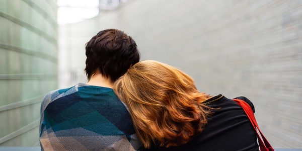 Due donne di spalle, una con capelli biondi lunghi e l altra con capelli corti mori guardano alla finestra. La donna bionda ha la testa appoggiata alla spalla della signora acconto a lei.