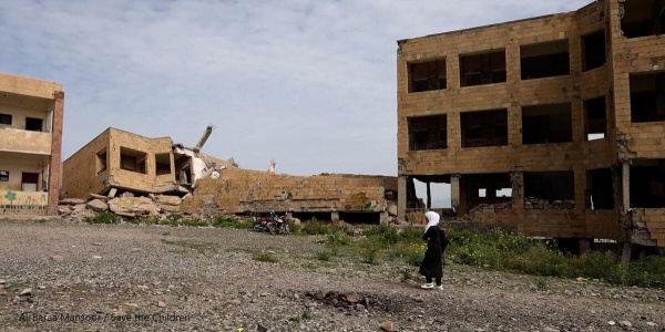 bambina in yemen con alle spalle palazzi distrutti 