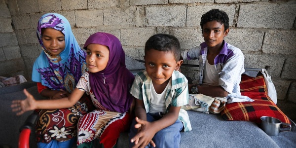 Quattro bambini yemeniti seduti sul letto insieme in una casa di mattoni