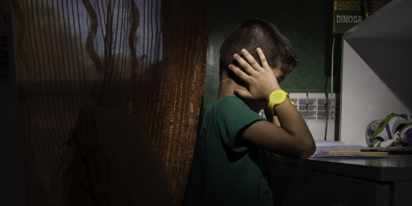 Bambino nella sua stanza buia si copre le orecchie con le mani