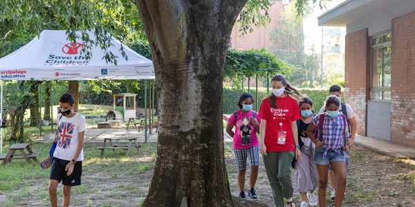 ragazzi e bambini che giocano e camminano attorno ad un albero 