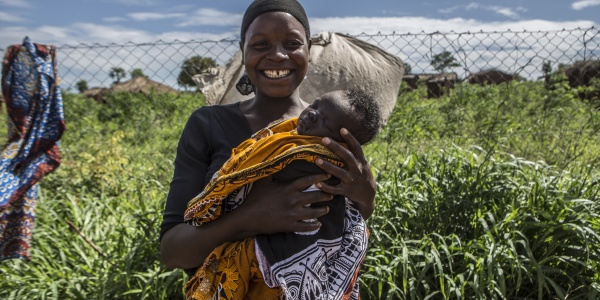 mamma sorridente con bambino in braccio in un campo