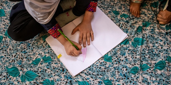 Bambina afgana che scrive su un foglio 
