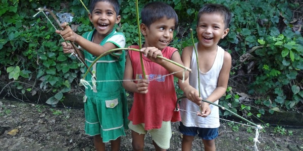 tre bambini indiani sorridenti con arco e freccia giocattolo che giocano insieme